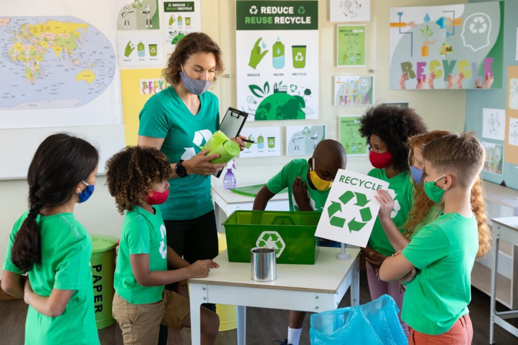 Caucasian female teacher wearing face mask at school, teaching children at school classroom.