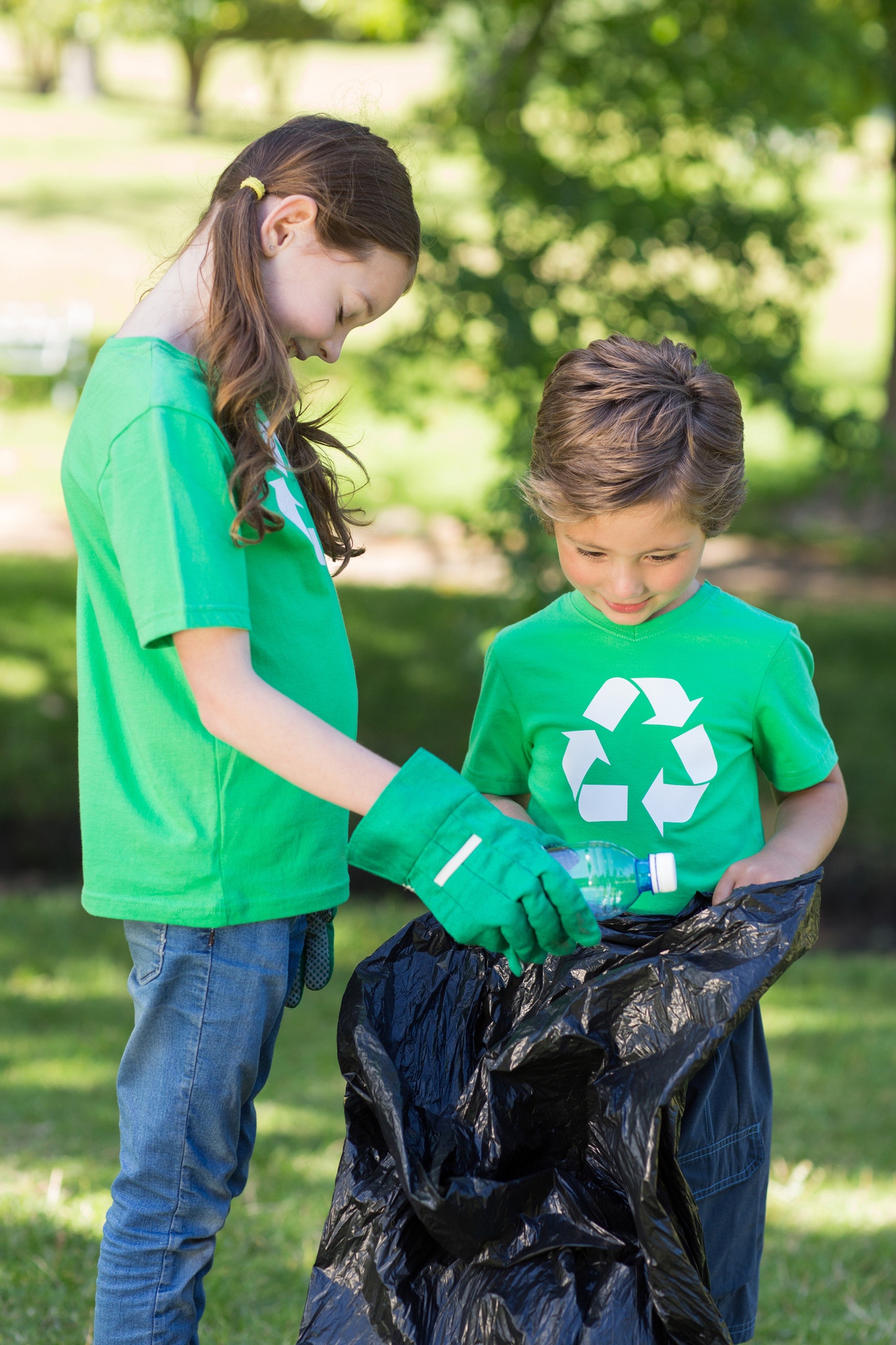 Happy siblings collecting rubbish on a sunny day


